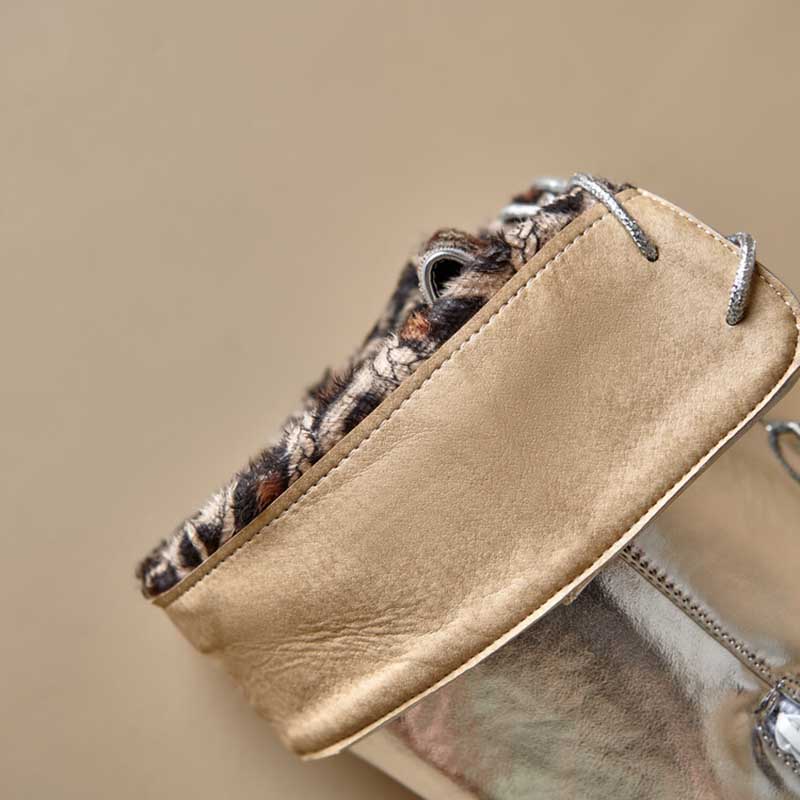 Close-up of beige lace up heeled boots for women with fur lining and silver laces