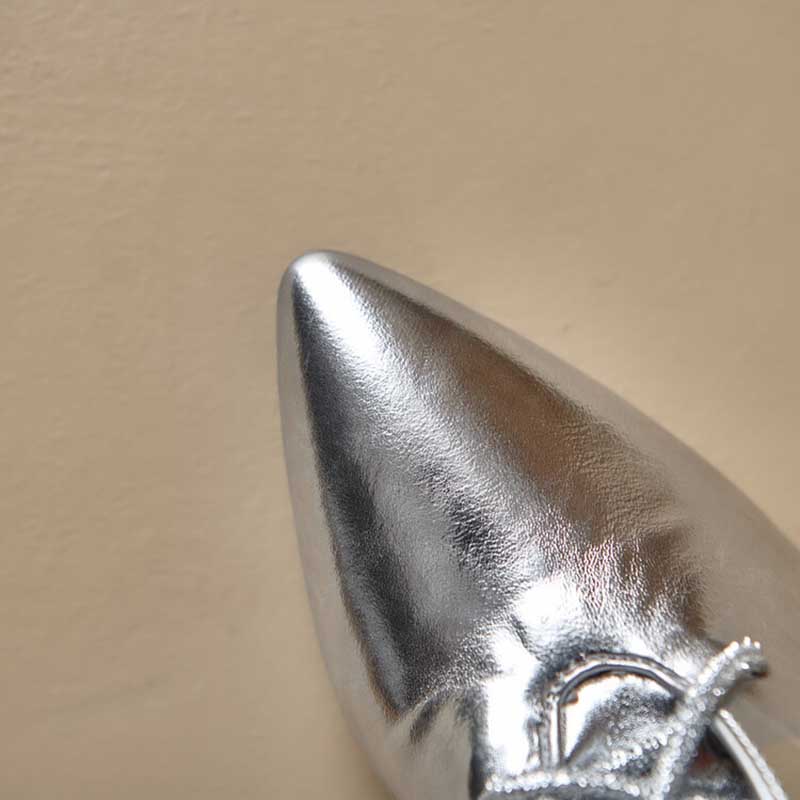 Close-up of silver lace up heeled boots for women with pointed toe detail on beige background