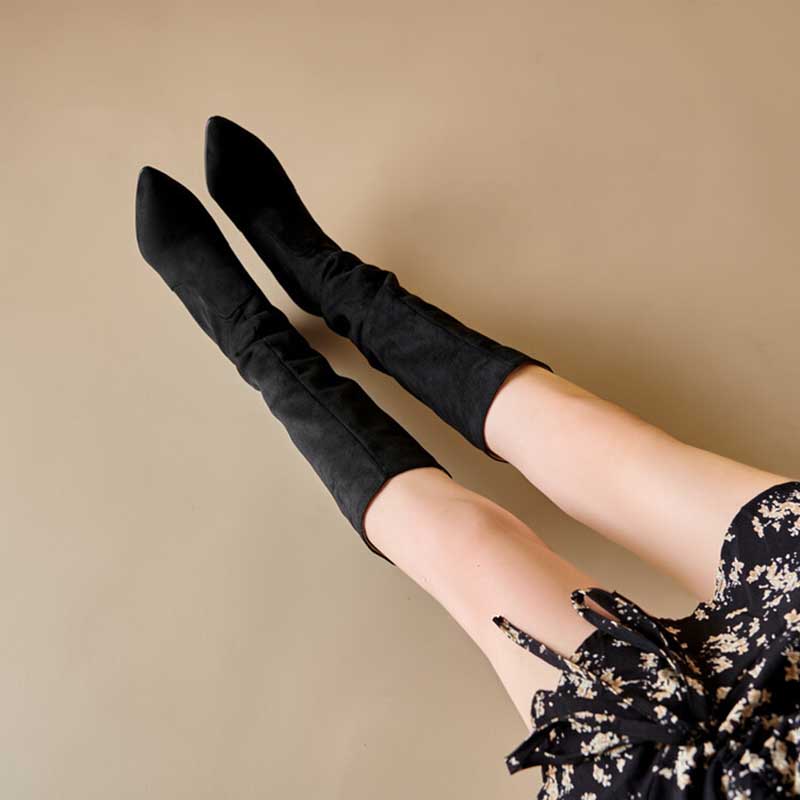 Black suede knee high boots for special occasions worn with a floral dress on model legs