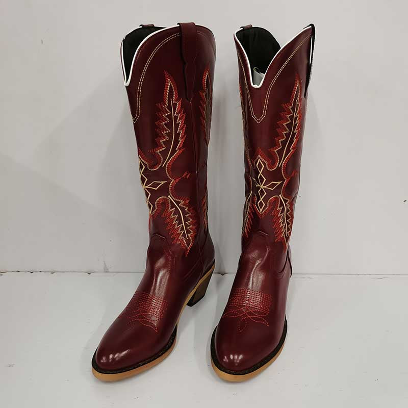Vintage knee high cowboy boots in dark red leather with intricate tan and orange stitching design