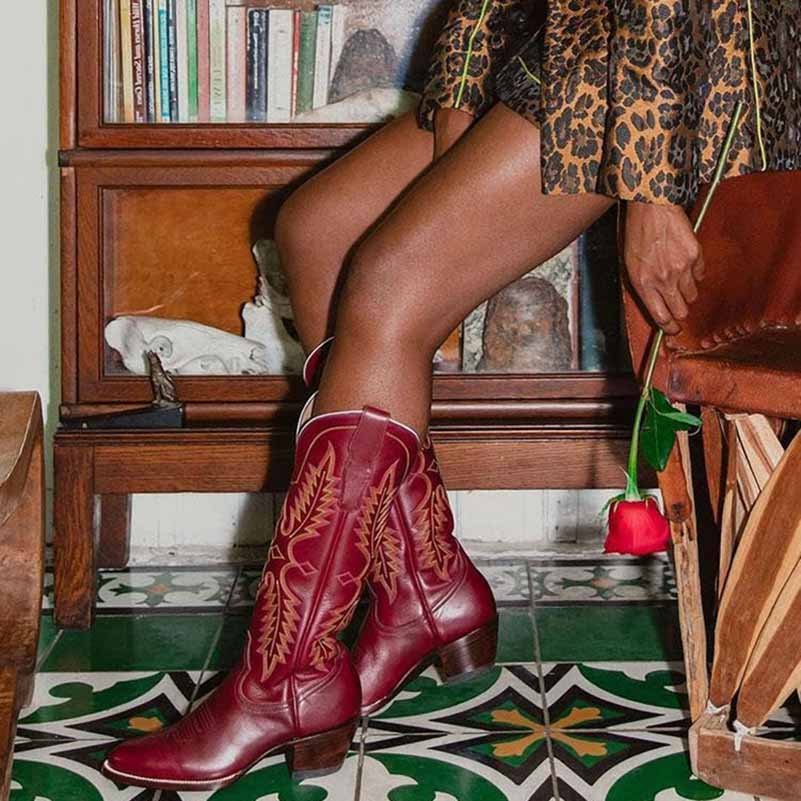 Vintage knee high cowboy boots in red with decorative stitching worn with leopard print dress indoors