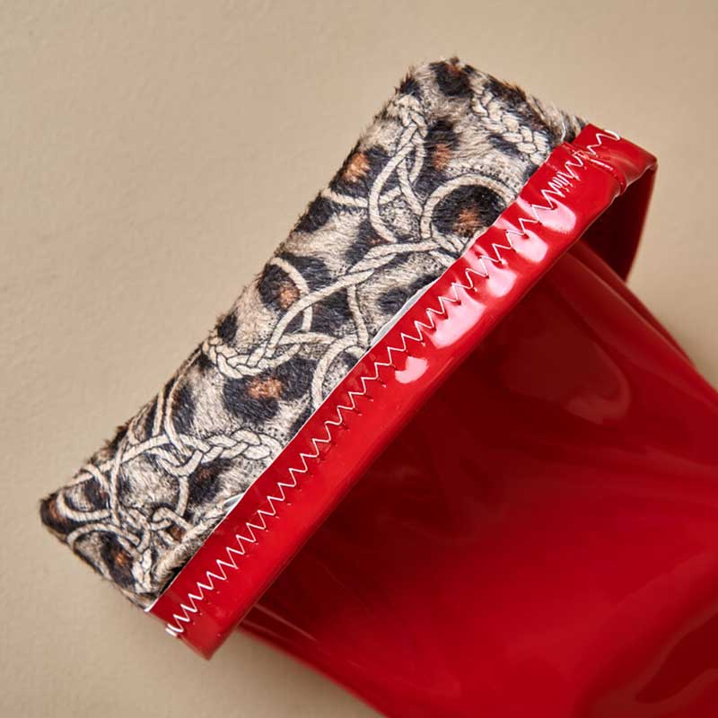 Close-up of women's chunky heel boots for prom with red shiny finish and leopard print fur trim