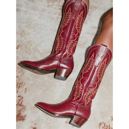 Vintage knee high cowboy boots in deep red leather with intricate tan stitching and wooden heels
